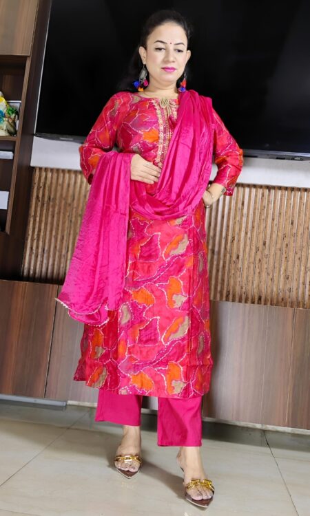 Woman wearing bright pink silk blend suit set with abstract multicolor print, embroidered neckline, and matching dupatta