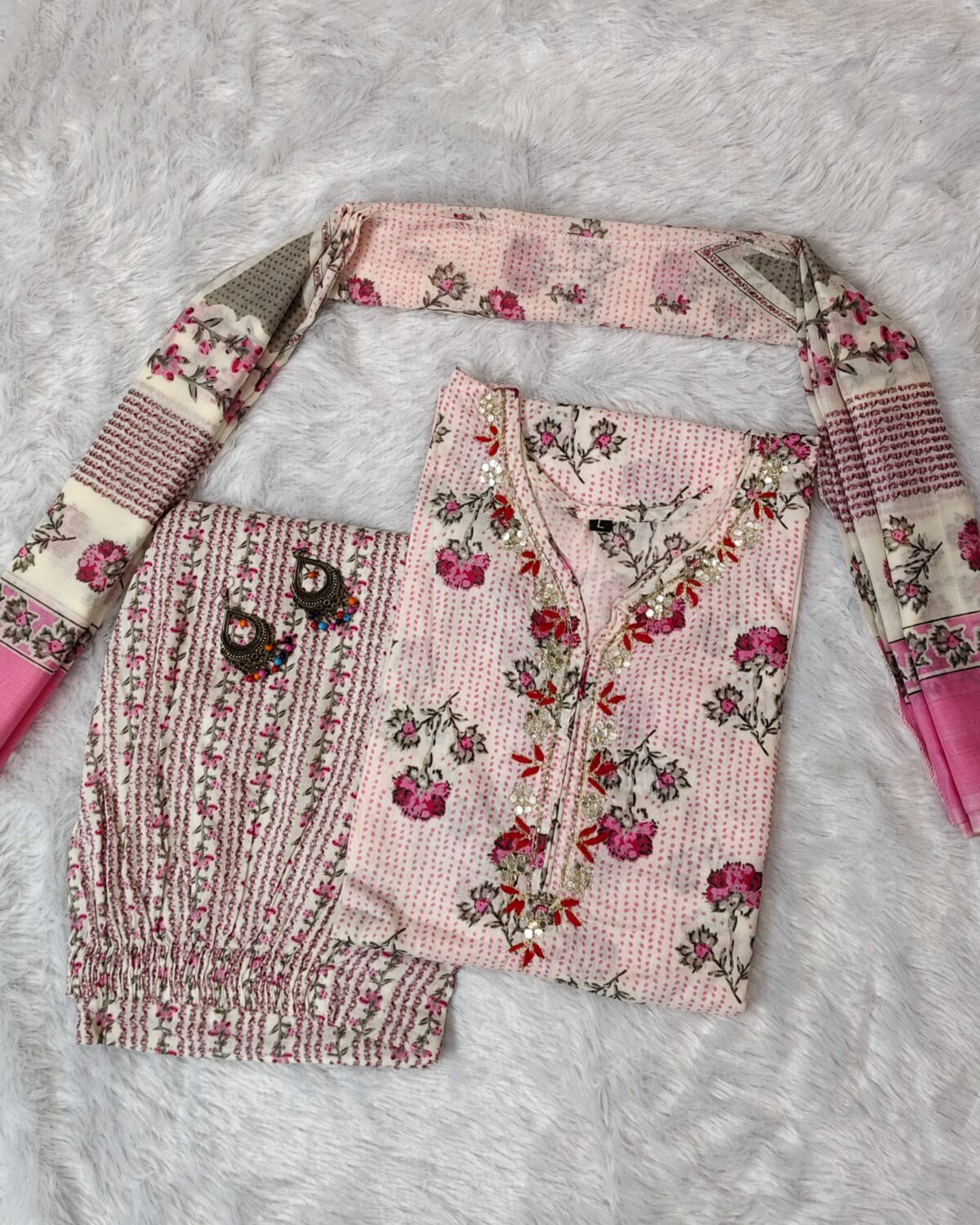 Woman wearing elegant white and pink floral Cambric Cotton suit set with kurta, printed pant, and dupatta – ethnic wear for women.