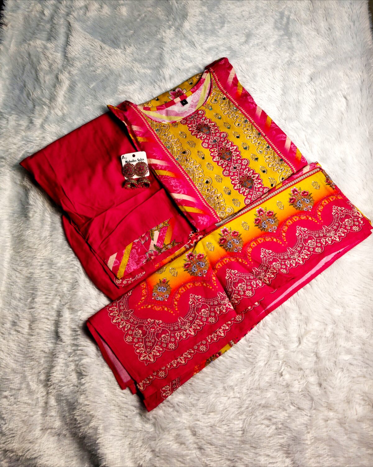Woman wearing vibrant yellow and pink embroidered muslin suit set with floral motifs and matching printed dupatta – festive ethnic wear.