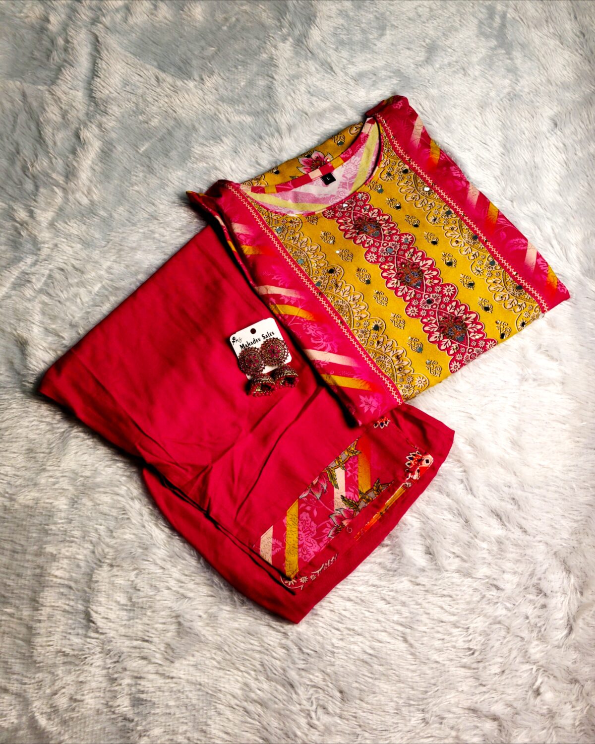Woman wearing vibrant yellow and pink embroidered muslin suit set with floral motifs and matching printed dupatta – festive ethnic wear.