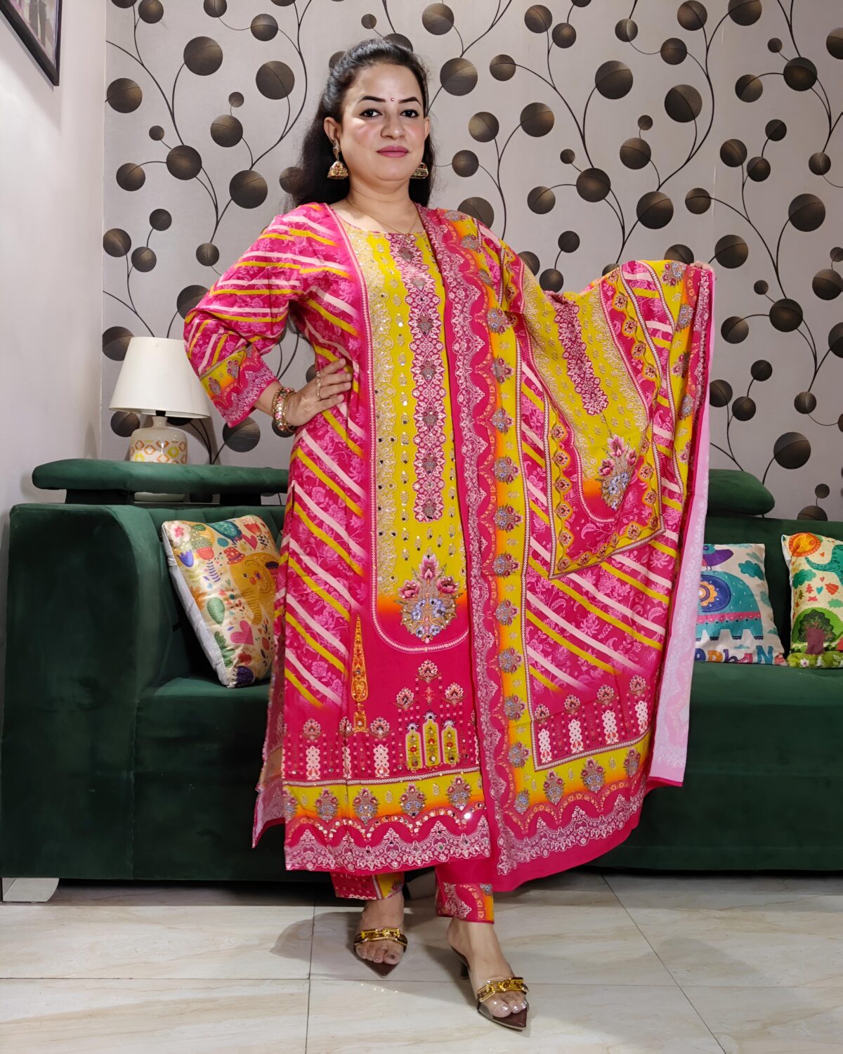 Woman wearing vibrant yellow and pink embroidered muslin suit set with floral motifs and matching printed dupatta – festive ethnic wear.