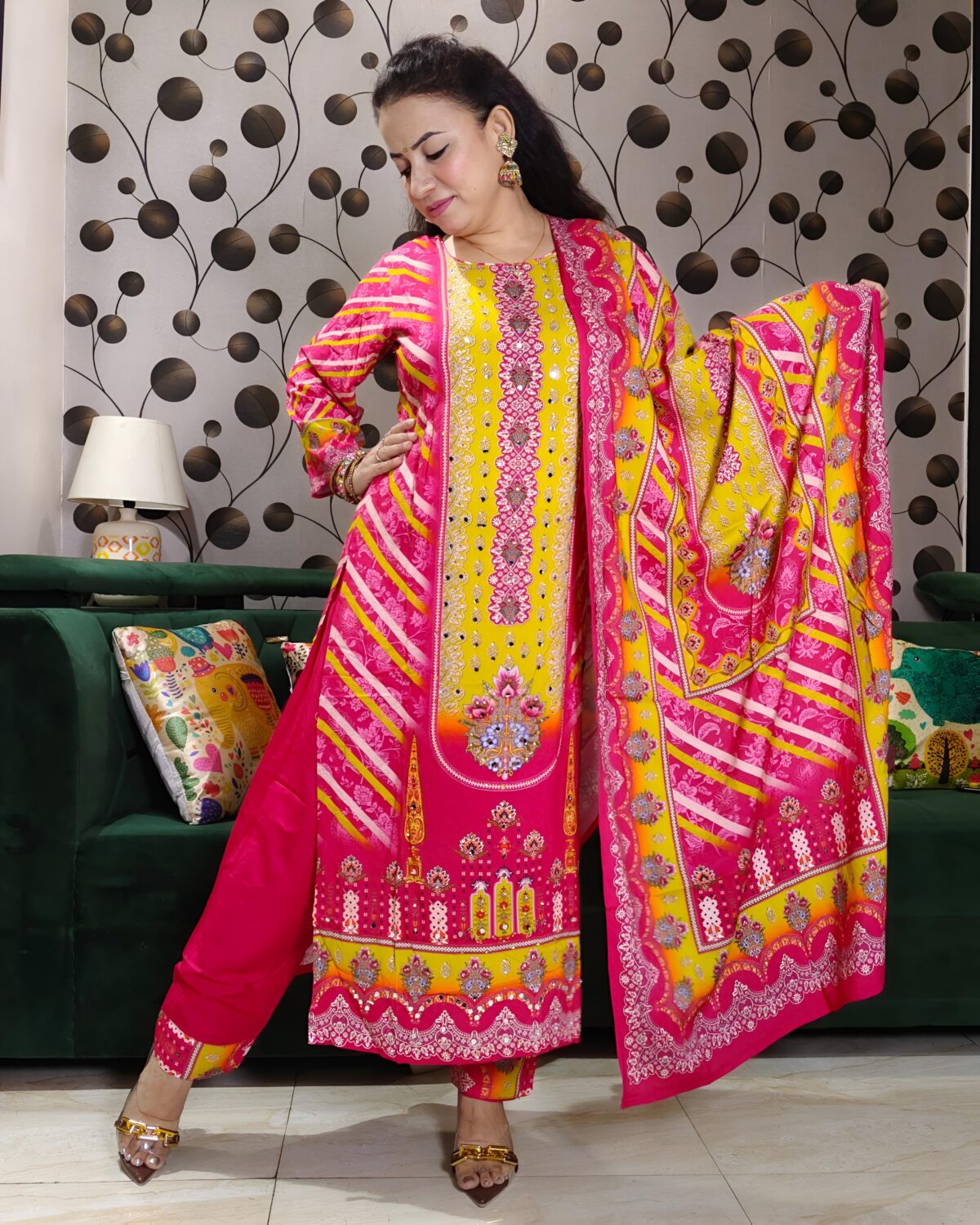 Woman wearing vibrant yellow and pink embroidered muslin suit set with floral motifs and matching printed dupatta – festive ethnic wear.