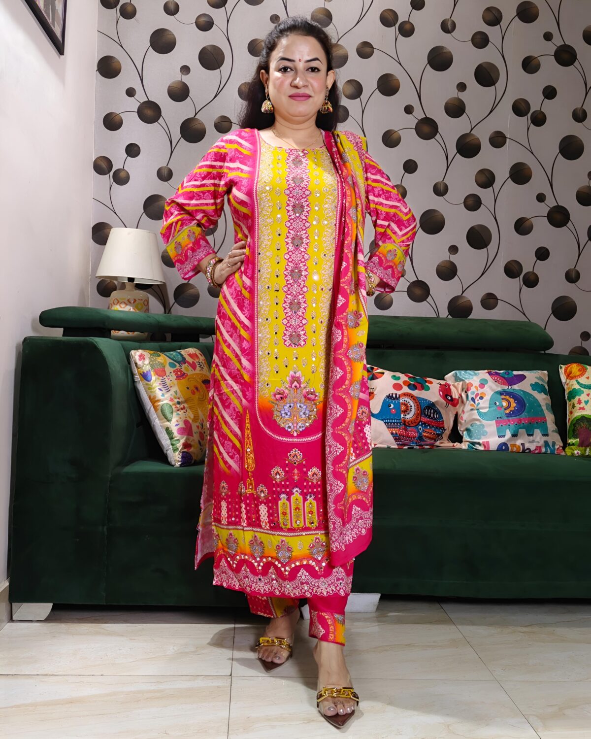 Woman wearing vibrant yellow and pink embroidered muslin suit set with floral motifs and matching printed dupatta – festive ethnic wear.