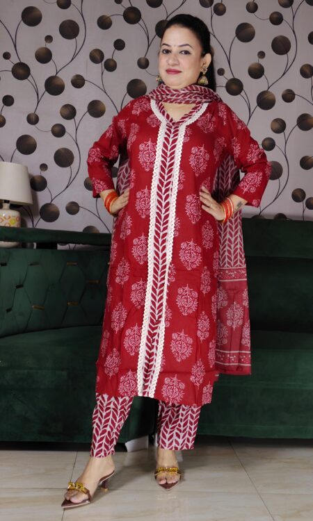 Woman wearing a premium rust handblock printed cotton suit set featuring lace-detailed V-neck kurta, printed pants, and matching dupatta.