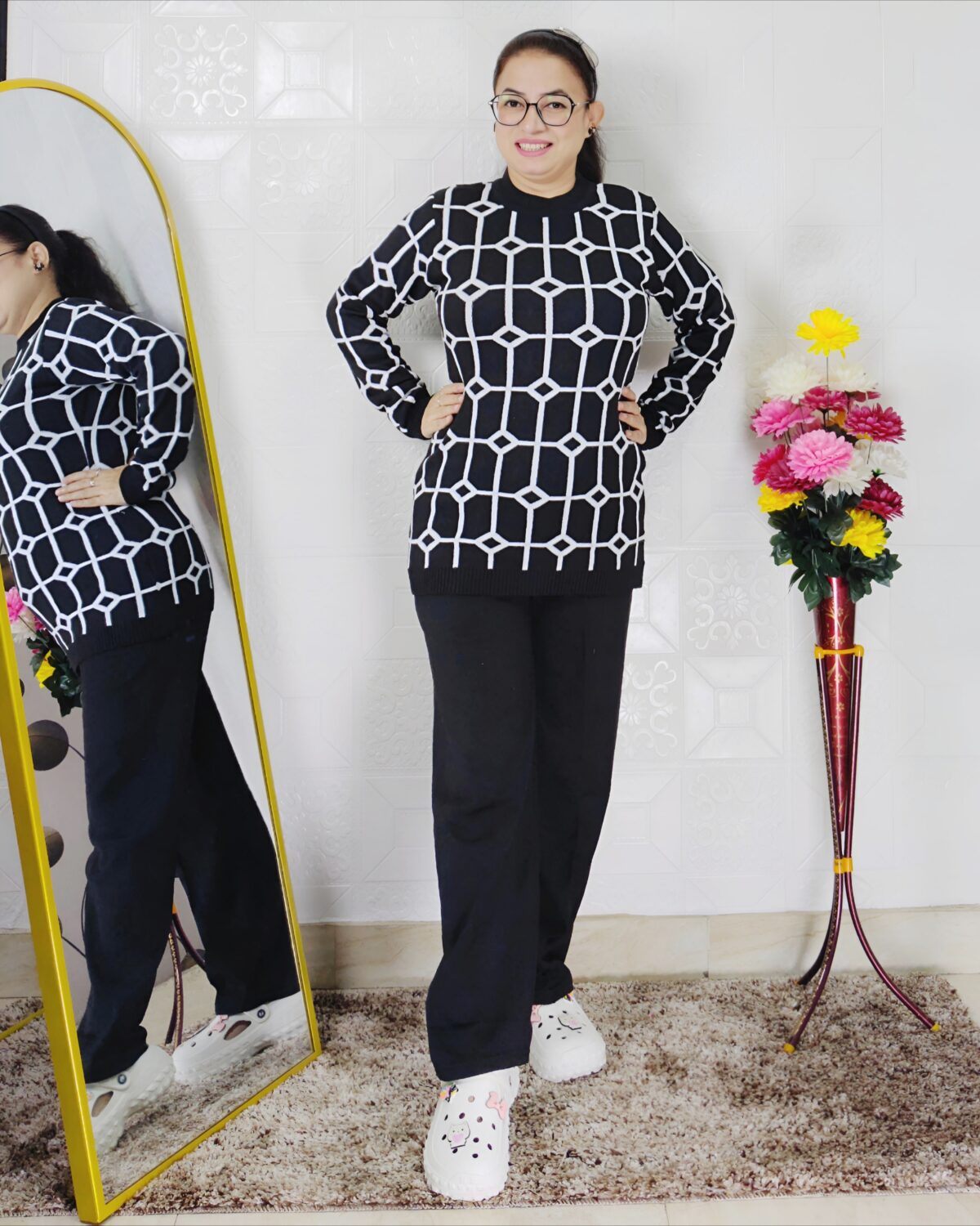 Woman wearing a black and white premium knitted co-ord set with a geometric patterned top and solid black pants