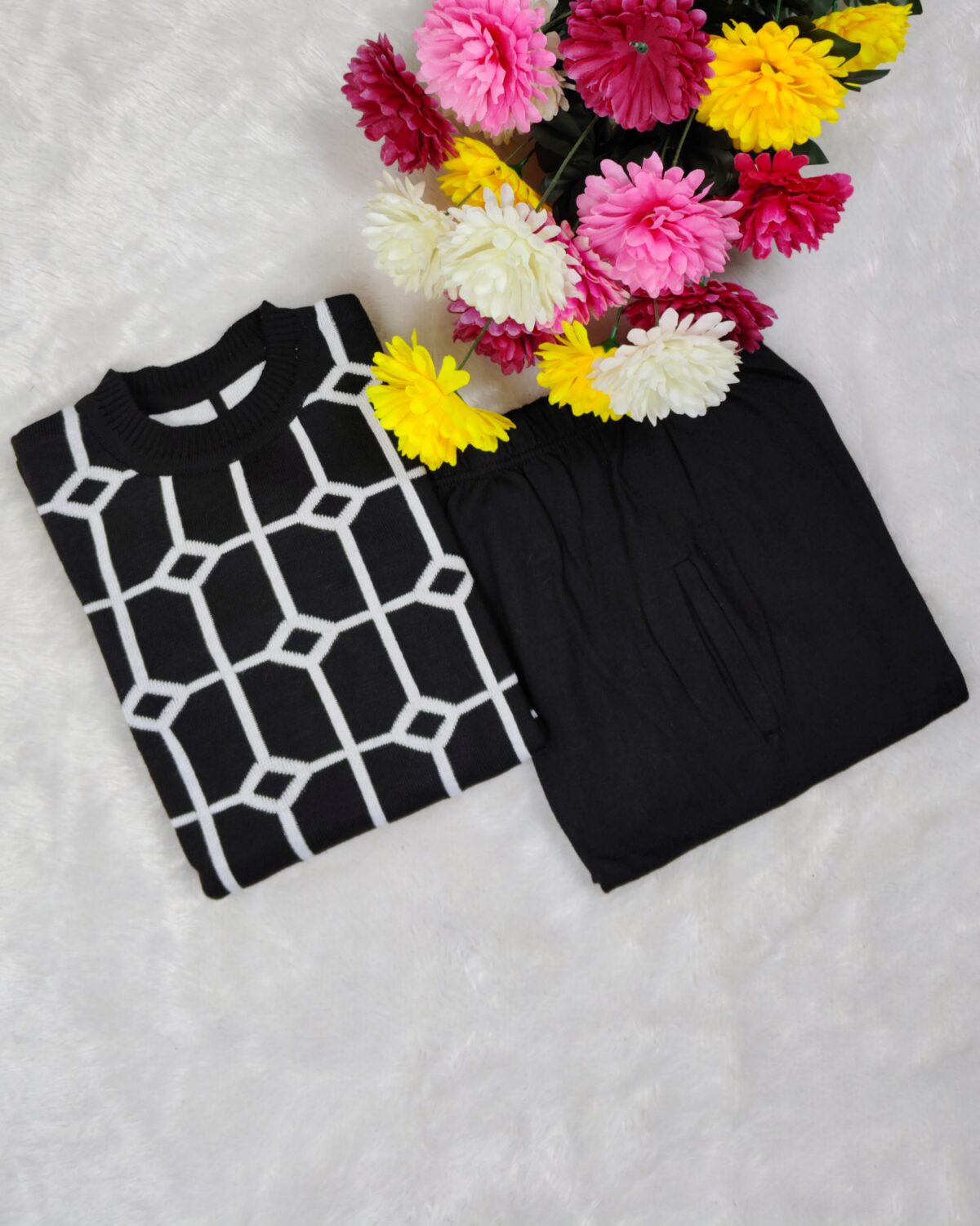 Woman wearing a black and white premium knitted co-ord set with a geometric patterned top and solid black pants