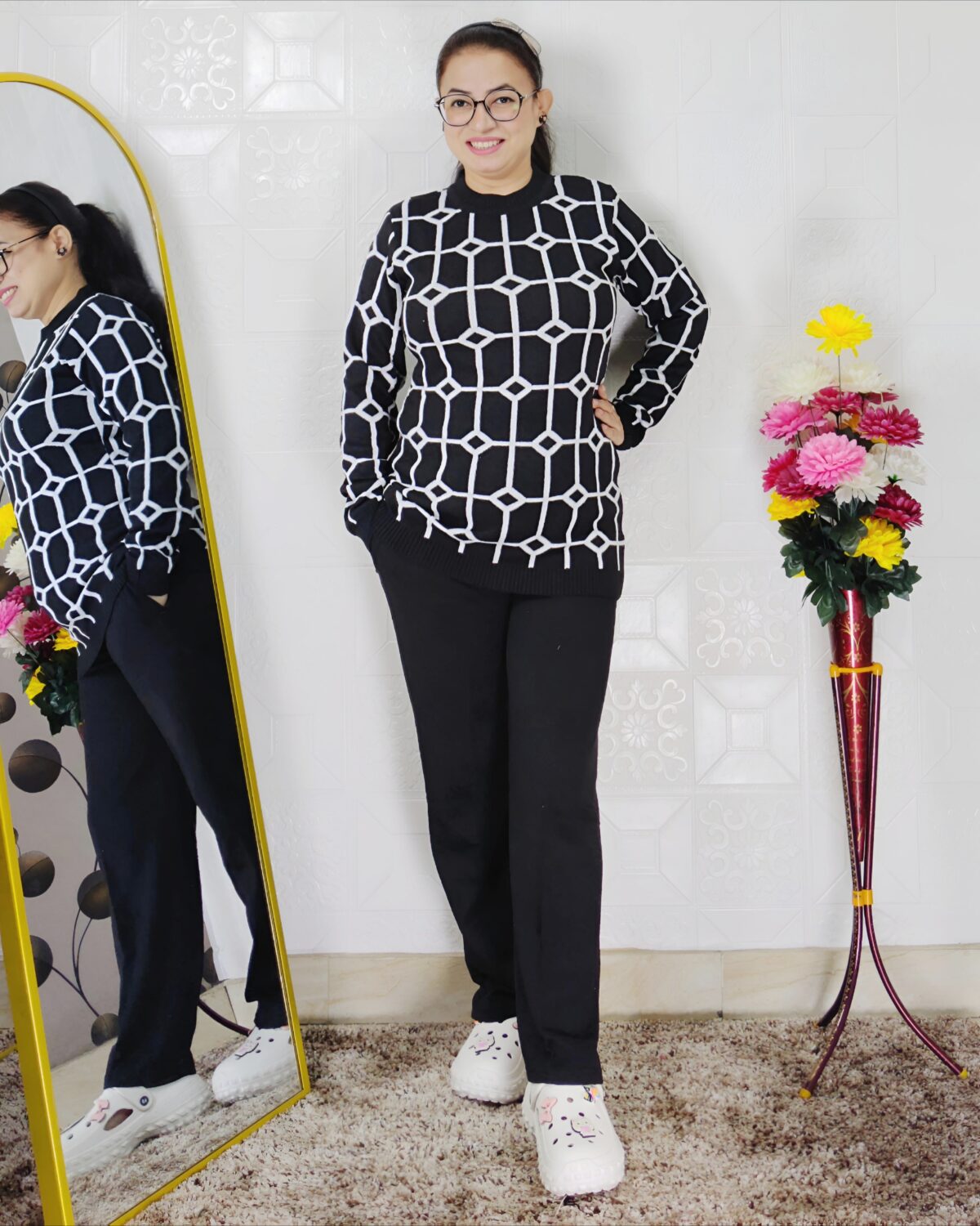 Woman wearing a black and white premium knitted co-ord set with a geometric patterned top and solid black pants